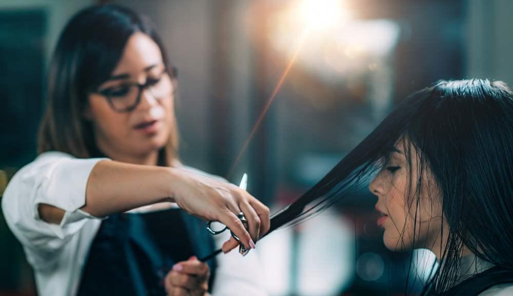 Young beautiful woman getting her hair cut by female hairdresser in beauty salon.